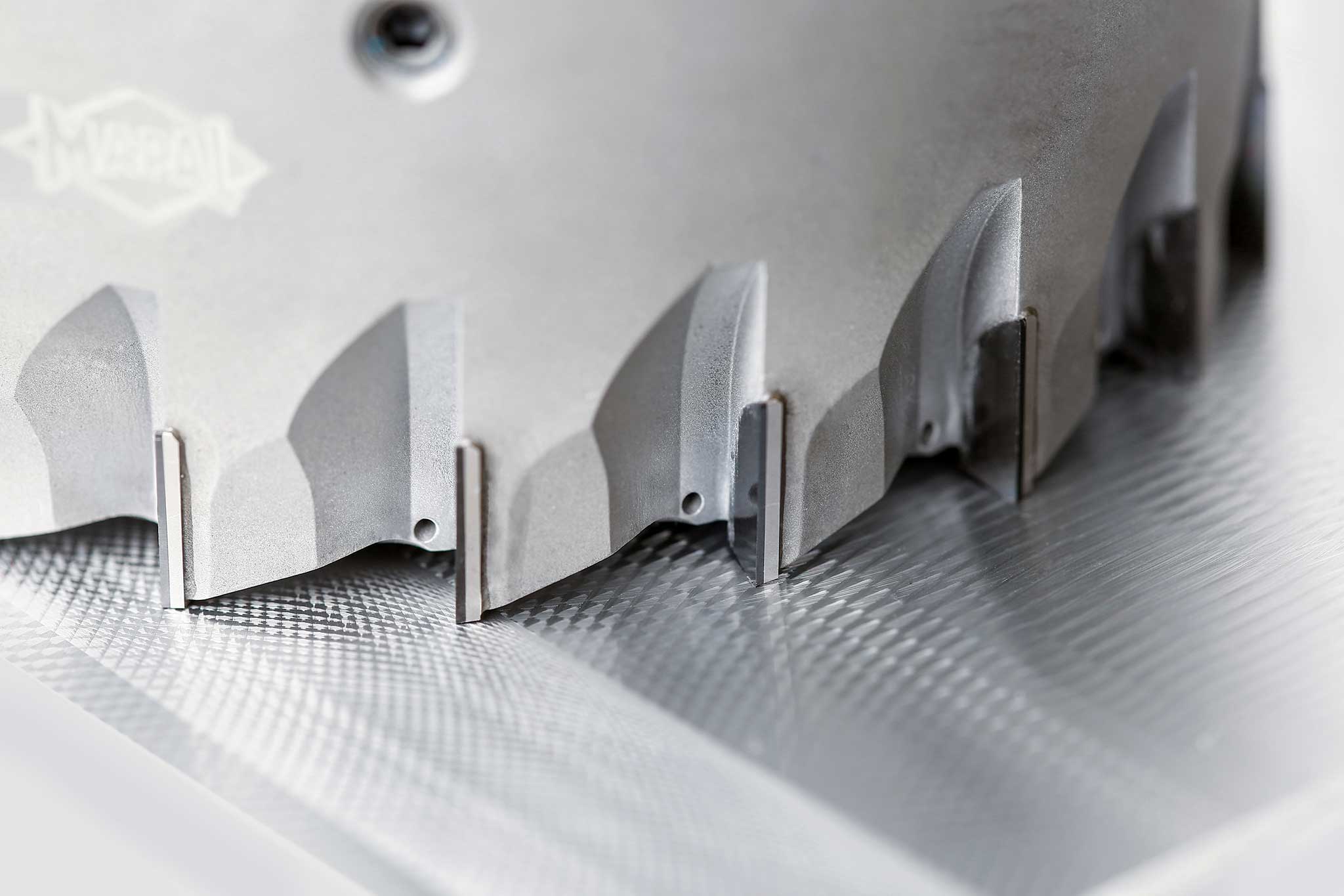 Mehrere Schneiden des FaceMill-Diamond auf einer bearbeiteten Oberfläche eines Aluminiumbauteils in Detailaufnahme.