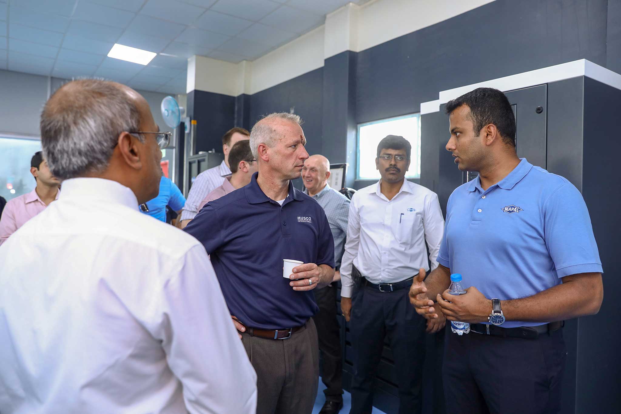 The participants stand in the tool management room. Centre: Bob Mortensen, President of Husco International.