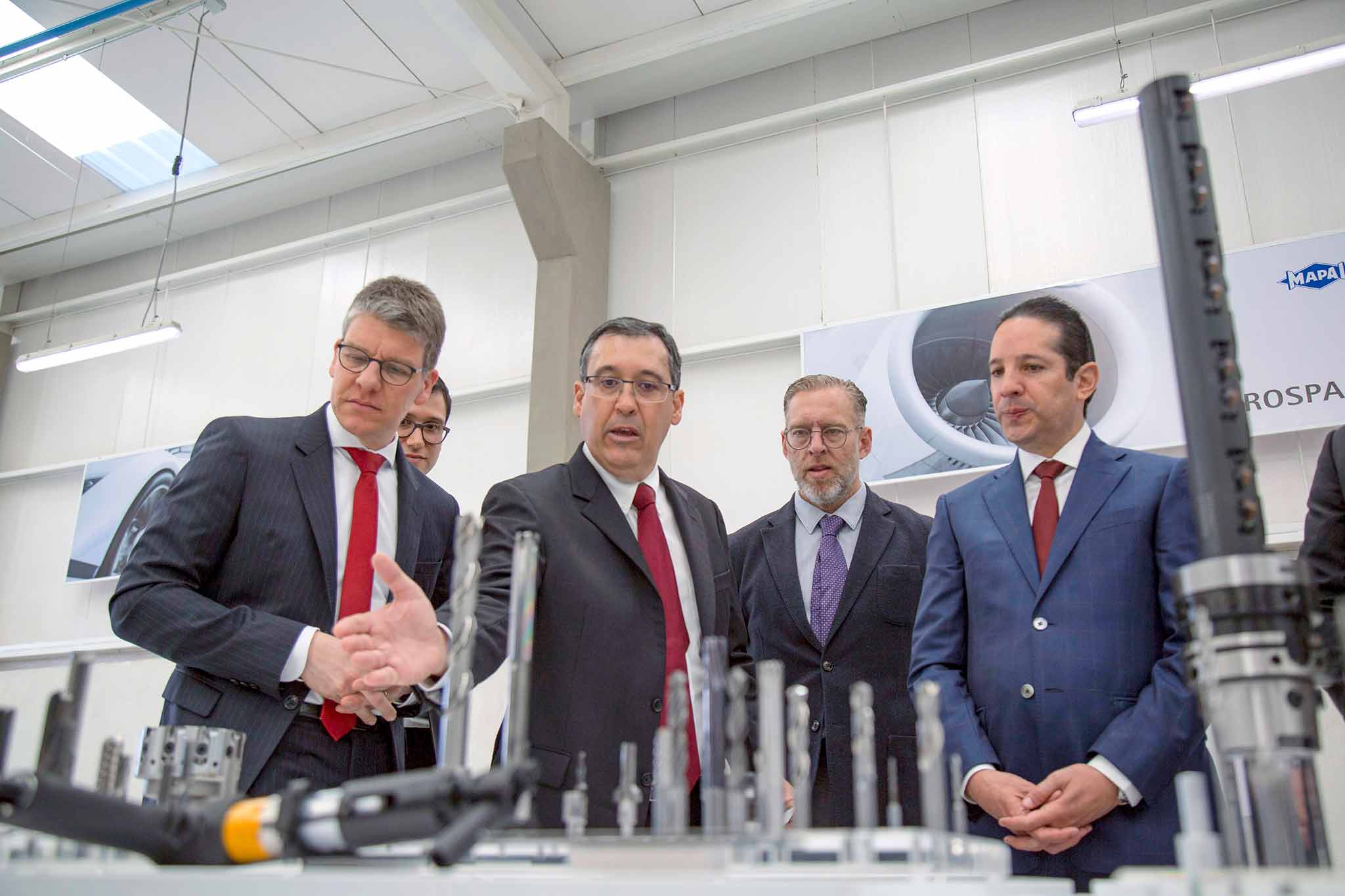 Leading figures from MAPAL and Dominguez Servién look at tools which are shown in the front section of the image.