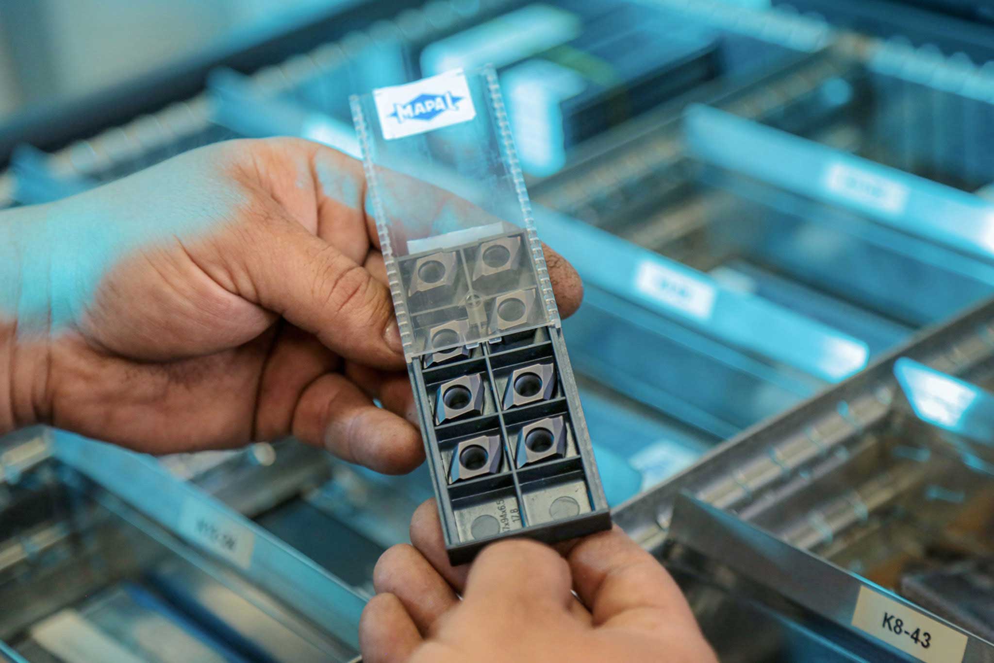 Im Bild halten die Hände eines Mitarbeiters der Hitachi Automotive Systems Group eine Verpackung mit Sonderschneiden.