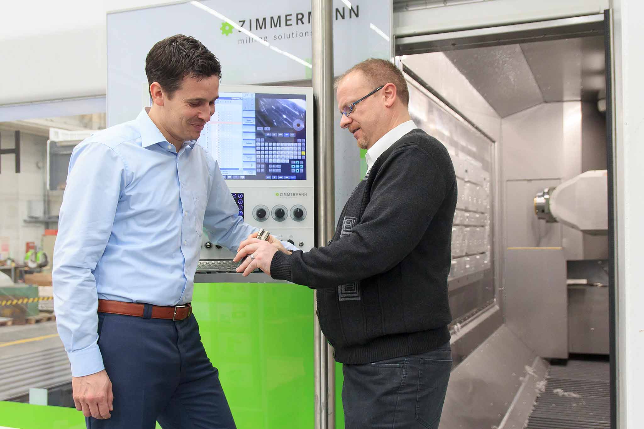 Dietmar Maichel und Steffen Nüssle stehen vor dem Horizontal-Bearbeitungszentrum FZH und unterhalten sich. 