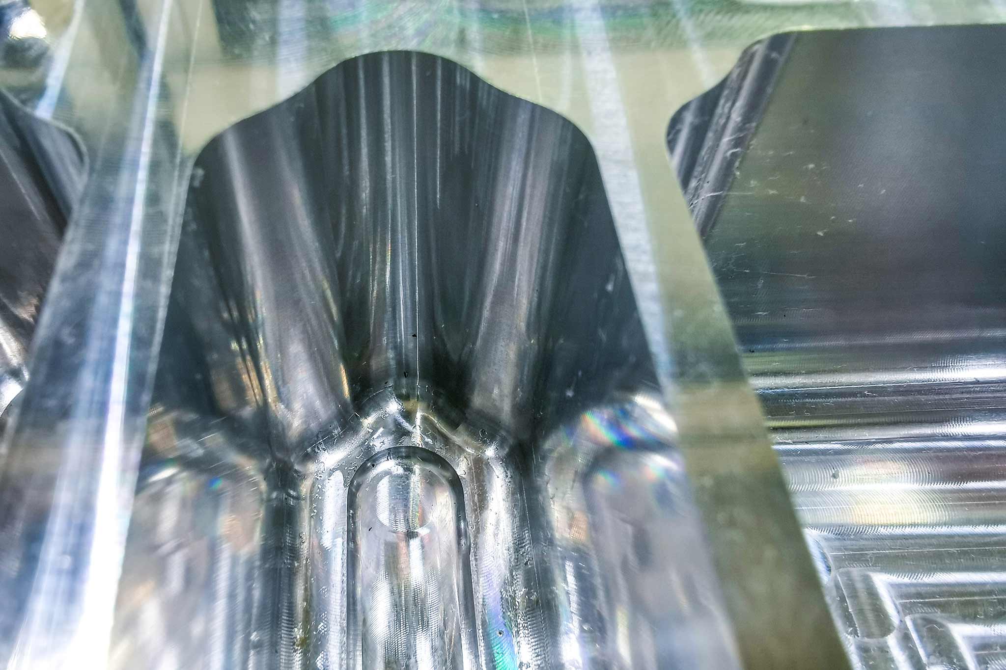 Ein Aluminium-Bauteil mit tiefen, engen Taschen im Eckenbereich ist auf dem Bild zu sehen.