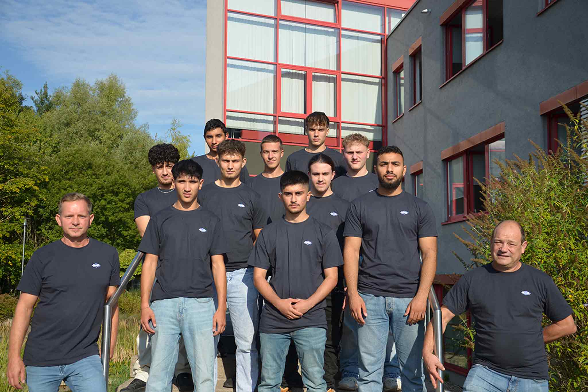 Die neuen Auszubildenden des Jahrgangs 2024 des Kompetenzzentrums Pforzheim mit ihren Ausbildungsverantwortlichen stehen vor dem Haupteingang.