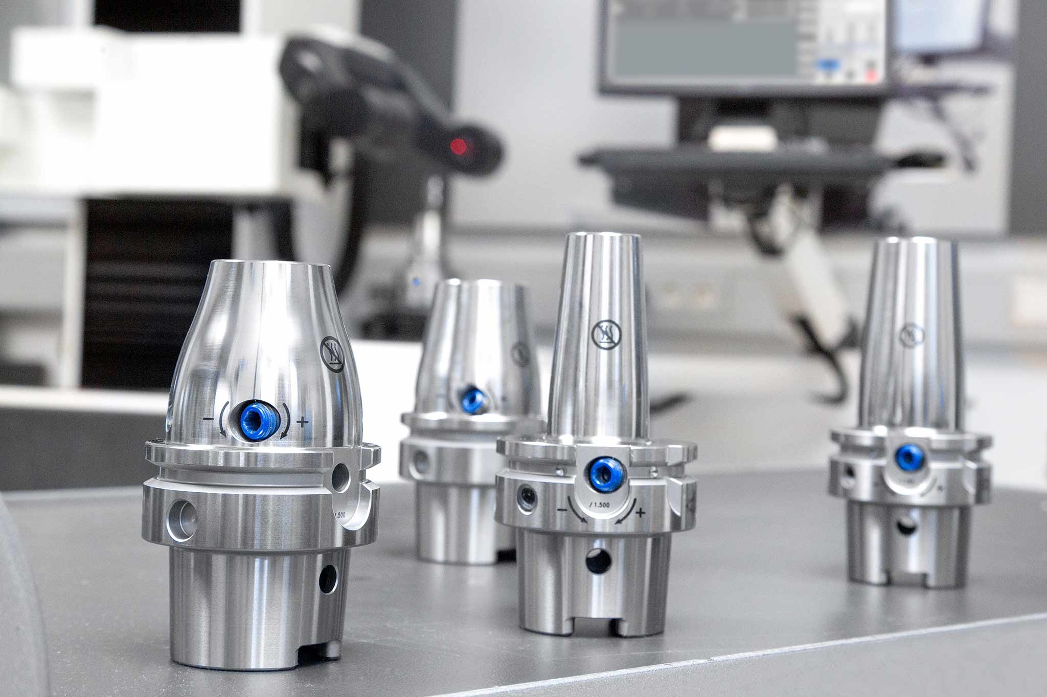 Mehrere Varianten der Hydrodehnspannfutter UNIQ von MAPAL sind auf einem Werkstattwagen in einem Einstellraum zu sehen.