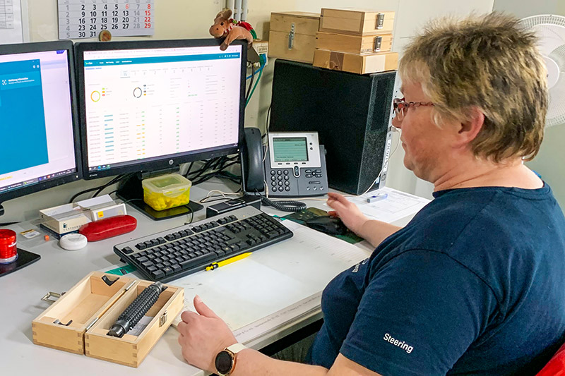 Eine Frau sitzt an einem PC-Arbeitsplatz und schaut in den Bildschirm, auf dem die c-Com Applikation läuft. 
