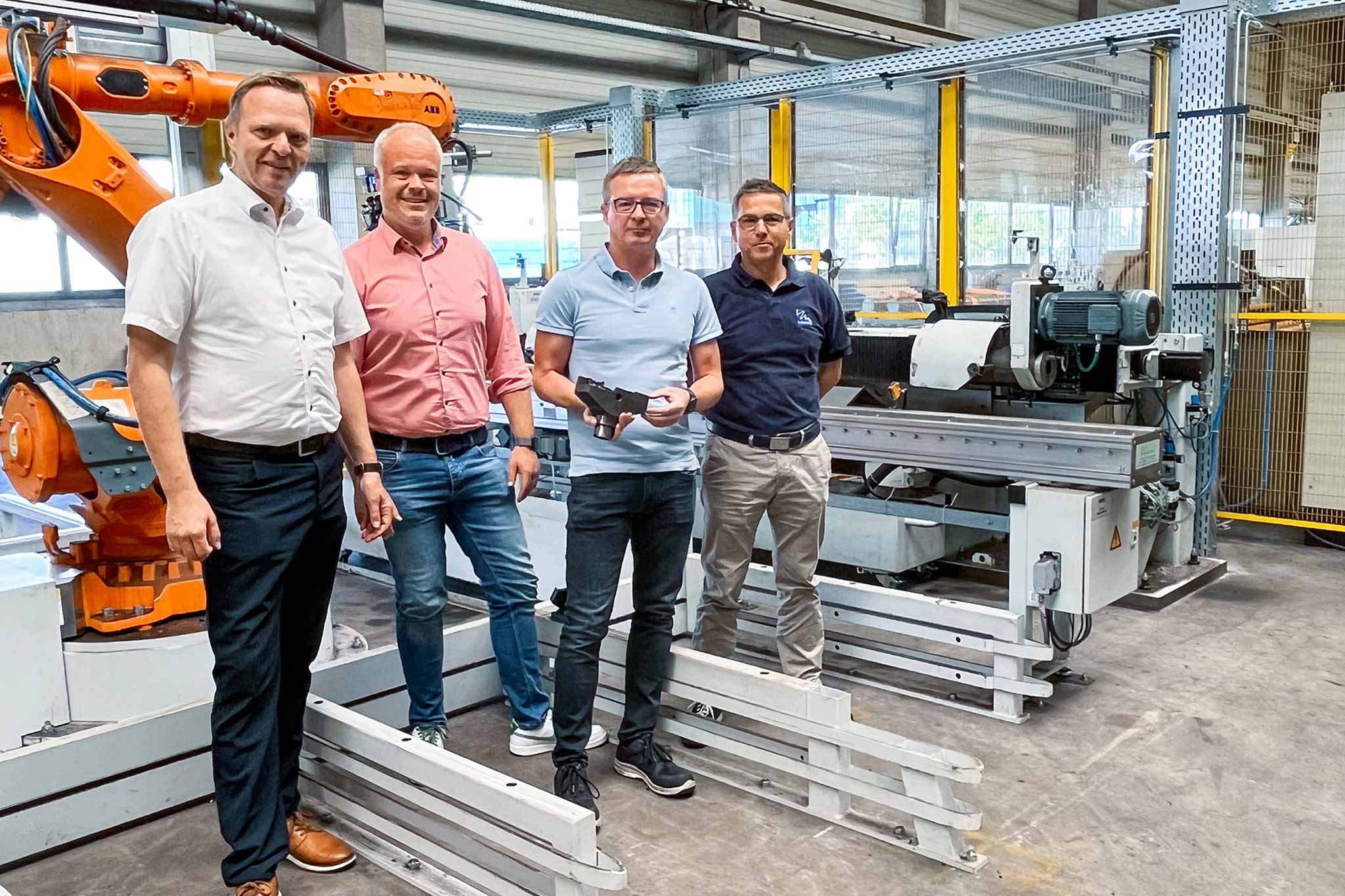 Das Bild zeigt eine Gruppe von Menschen in einer Maschinenhalle. 